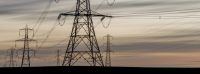 Image of electricity pylons in a field at sunset